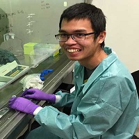 A student smiling while working near lab equipment